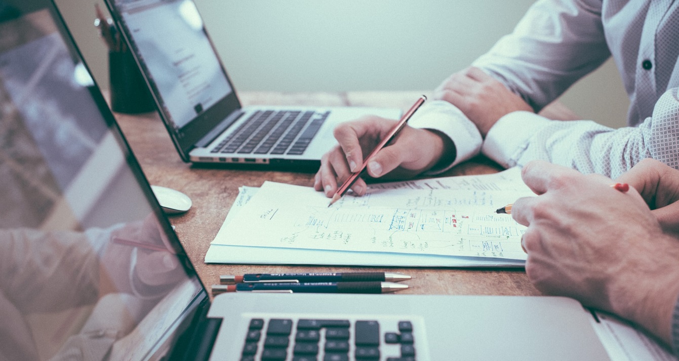Photo d'un bureau avec un ordinateur et quelqu'un qui écrit